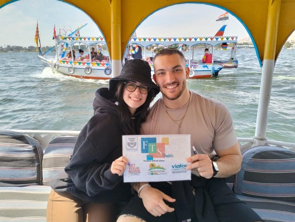 Couple on a boat with a travel sign on the Nile.