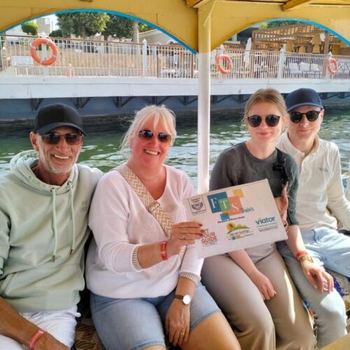 Family on a boat in Luxor smiling and holding a sign.