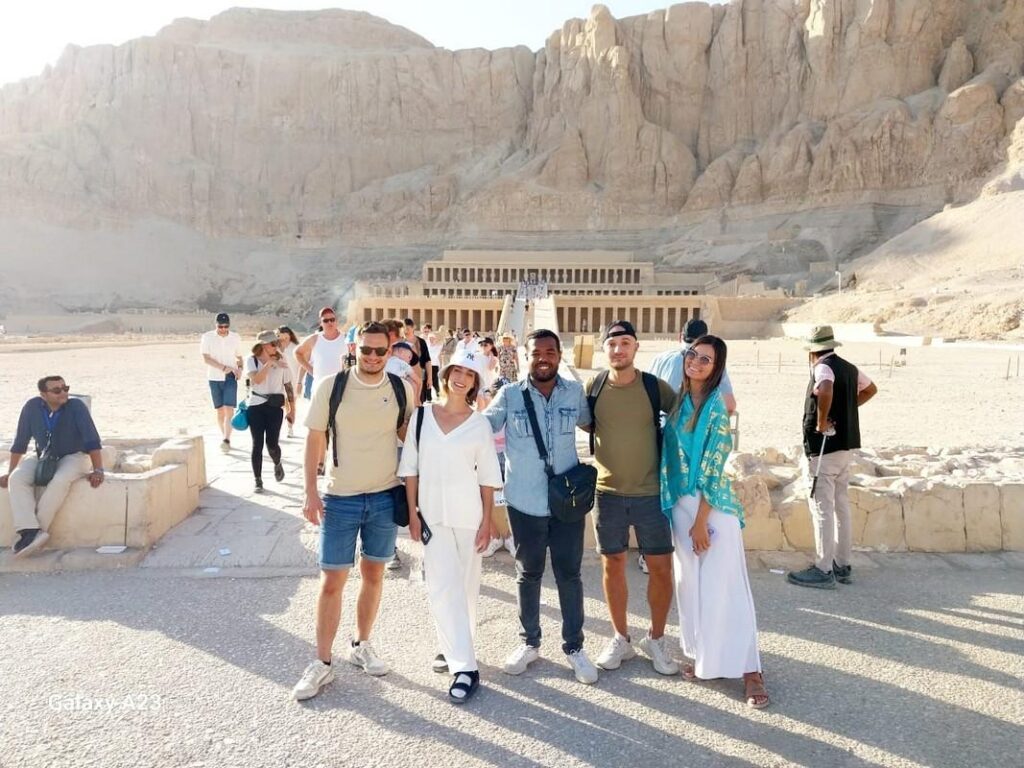 Tourists in front of Hatshepsut Temple with cliffs behind