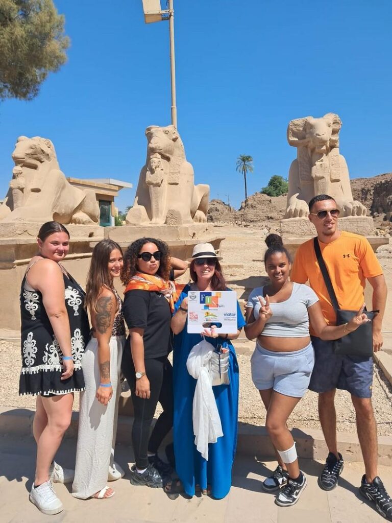 Travelers posing with ancient lion statues in Egypt.