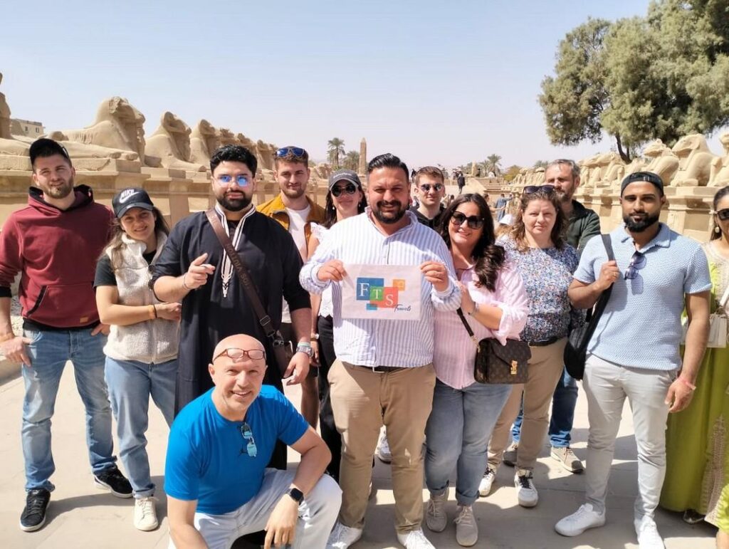 Tourists posing with ancient sphinxes in the background.