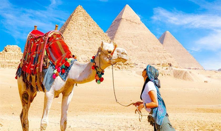Woman interacting with camel near pyramids