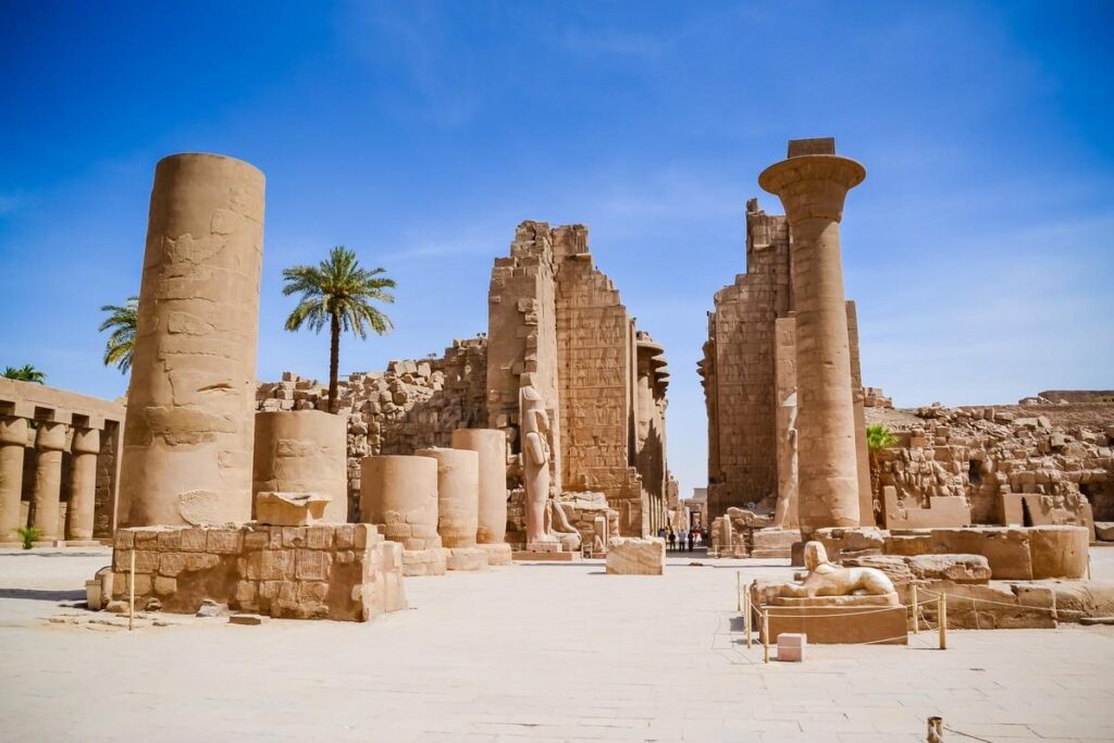 Ruins of Luxor Temple with columns and palm trees
