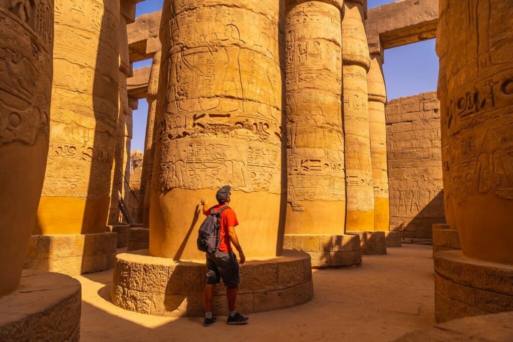 Visitor studying hieroglyphs on ancient temple columns