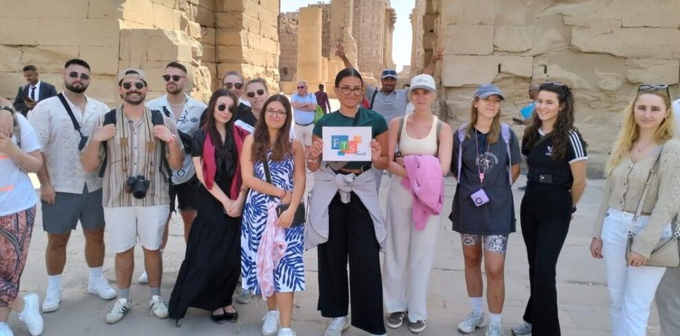 Tourists posing in front of ancient stone structures.