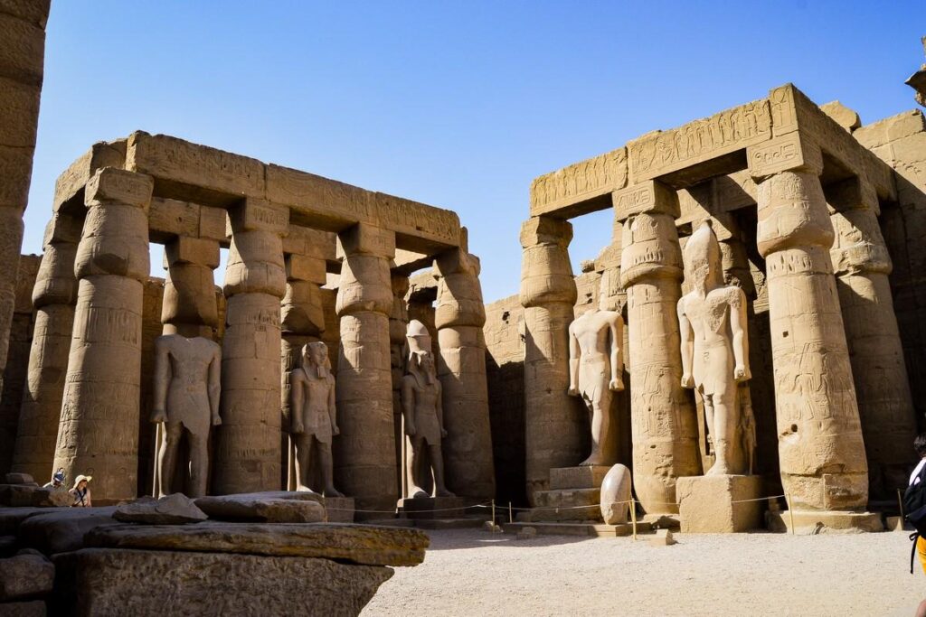 Tall ancient statues and columns in a temple courtyard