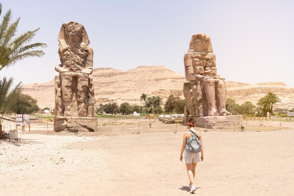 A person walks near the Colossi of Memnon in Egypt.