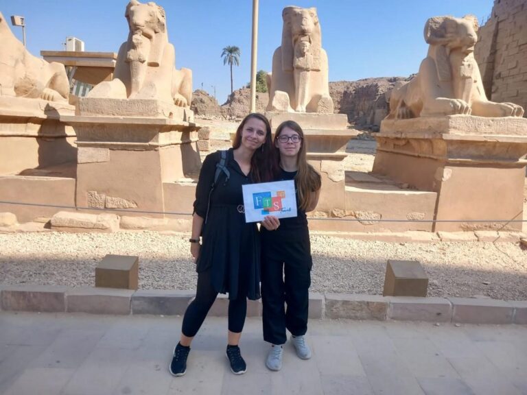 Two women in front of lion statues at an ancient site.